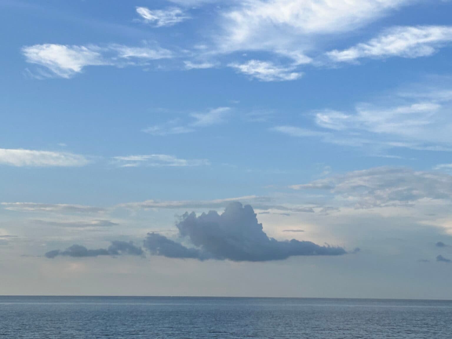 A serene seascape featuring a calm ocean under a partially cloudy sky. A serene seascape featuring a calm ocean under a partially cloudy sky.