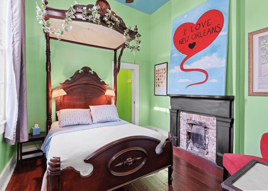 Brightly colored bedroom featuring a four-poster bed, a painted wall with a heart design, and a cozy atmosphere.