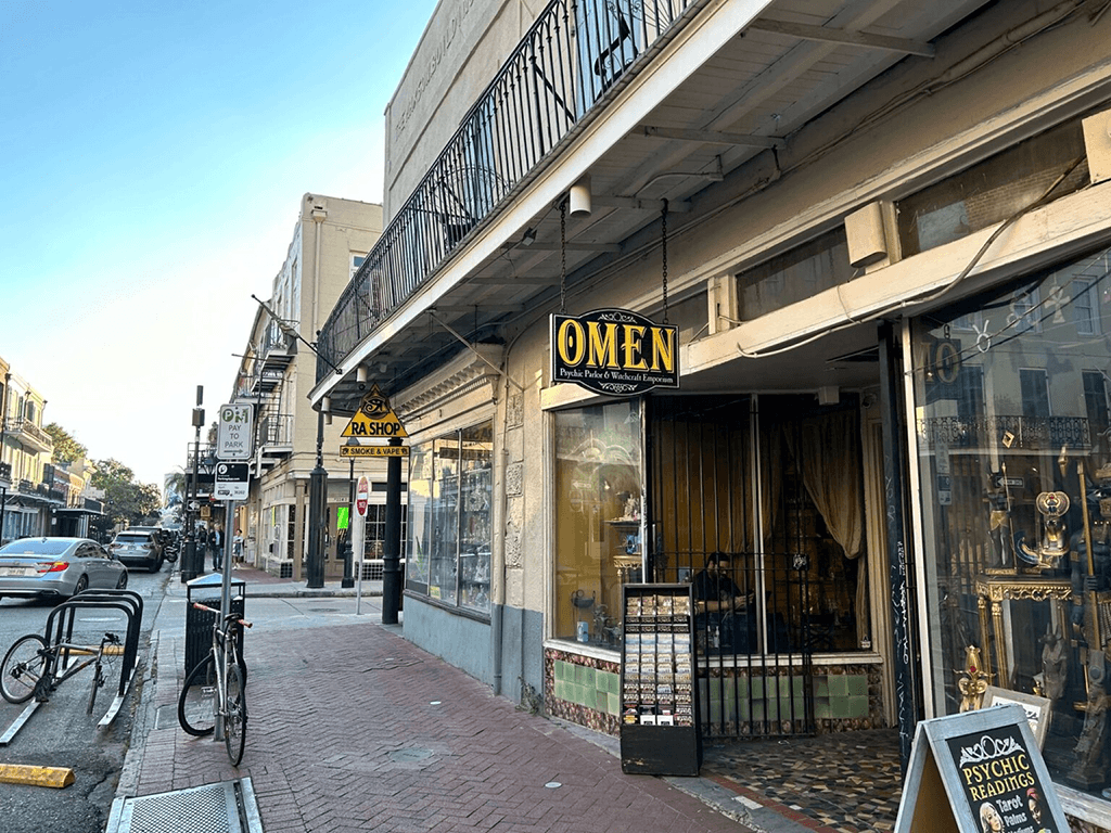 A street view of a storefront named "OMEN," featuring a psychic readings sign and an inviting window display.